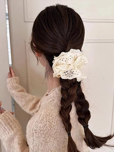 Detailed view of cream lace scrunchie with intricate embroidery on braided hair