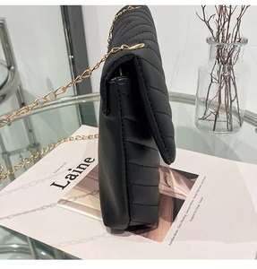 Detail view of black quilted crossbody bag with gold chain and chevron pattern