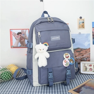 Detail of grey-blue school backpack with cute bear pendant and decorative badges