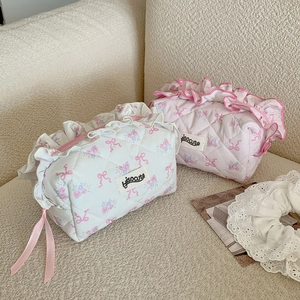 Detail of floral quilted makeup bags with ribbon lace and ruffled edges on a soft sofa
