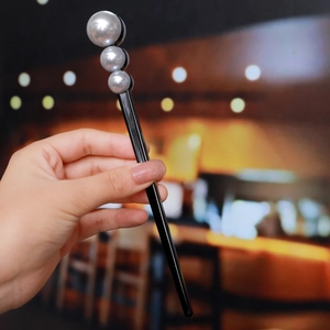 Detail of elegant black hair stick with three glossy pearls for modern women hairstyles