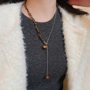 Detail view of brown tiger eye beaded necklace with silver chain on model neck