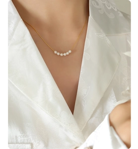 Close-up of minimalist gold plated chain with six small pearls in crescent arrangement