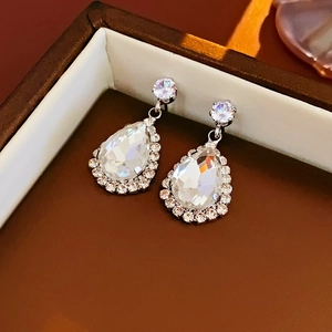 Gros plan de boucles d'oreilles en cristal de poire argentées avec halo de zircones