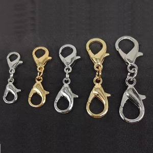 Detail showing silver and gold metal lobster clasps in various sizes on dark surface