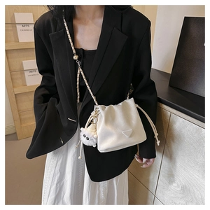Detail of a white bucket bag with leather-threaded chain strap and a plush sheep charm