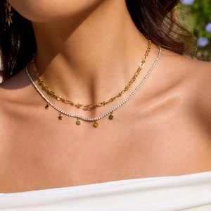 Detail of layered gold link chain and silver heart moon pendant necklace on model
