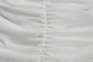 Gros plan sur un tissu léger blanc montrant des fronces verticales et des plis détaillés