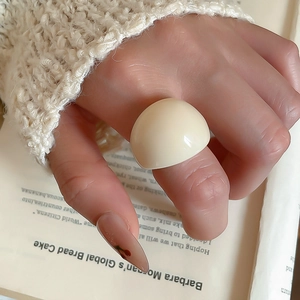 Detail of a minimalist beige resin ring on a hand with vintage book background
