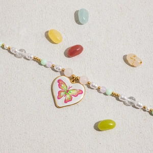 Détail du collier en acier doré 18K avec pendentif cœur et perles colorées