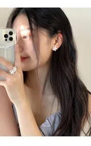 Detailed close-up of white flower pearl ring and stud earrings on model in soft light