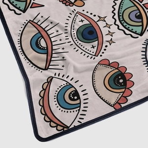 Detail of soft flannel blanket featuring colorful evil eye patterns and durable navy edges