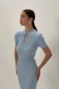 Dettaglio di un abito in maglia azzurra con scollo a lacetti traforato e maniche corte