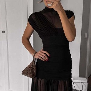 Detail of high neck black sleeveless dress featuring sheer mesh patchwork and ruched fabric