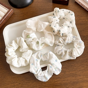 Detail of floral lace scrunchies with bow ribbons on a tray for elegant hair styling