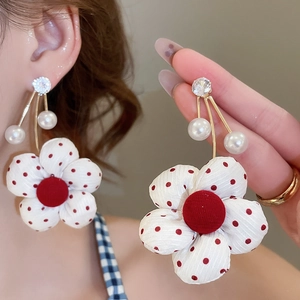 Detail of floral earrings featuring red polka dot fabric petals and white faux pearls