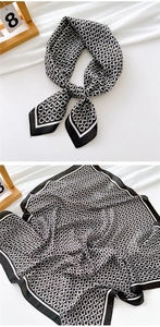 Detail of a black and white geometric chain print silk square scarf tied in a knot