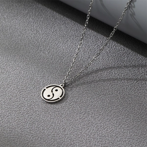 Silver stainless steel necklace with Bagua Tai Chi pendant on a textured surface