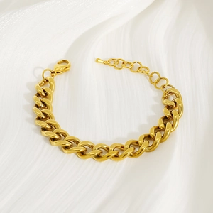 Detail of 18k gold chunky Cuban chain bracelet with lobster clasp on white texture