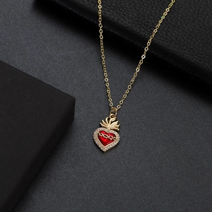 Macro detail of a gold heart pendant necklace with red zircon and sparkling accents