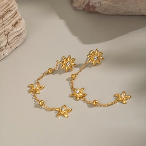 Detail of gold tassel earrings with starburst charms and inlaid clear crystals