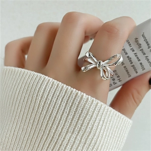 Close-up of 925 sterling silver bow ring on finger with white knit sleeve background
