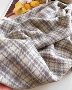 Detail of soft cream plaid cashmere-like scarf texture with grey and tan fringes
