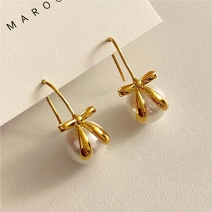 Macro view of French vintage bow pearl earrings with polished gold finish hooks