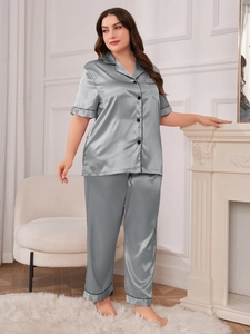 Detail of silver silk satin pajamas set featuring short sleeve shirt with black piping details