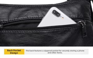 Close-up of the rear anti-theft zipper pocket on a black pebble leather crossbody bag