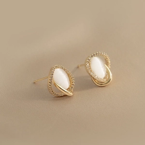 Elegant gold oval opal earrings with sparkling crystal halo on beige background