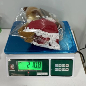 Detail showing the exact weight of the red and grey plush Christmas moose doll on a scale