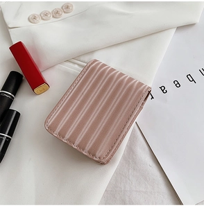 Detailed view of a pink striped mini cosmetic bag with mirror on a white blazer background