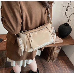 Détail du sac bandoulière beige en similicuir avec poches zippées et pompons déco