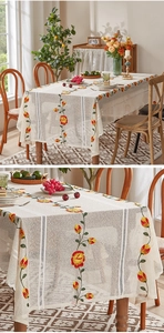 Detailed embroidery of yellow flowers on a beige lace tablecloth for dining table
