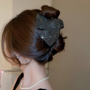 Close-up of a luxury black rhinestone bow hair claw clip worn on a bun hairstyle