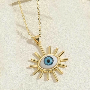 Detailed close-up of golden evil eye pendant with blue resin eye and sunburst eyelash charm