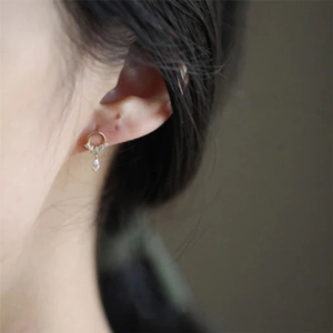 Close-up of golden water drop tassel earrings with sparkling crystals on ear