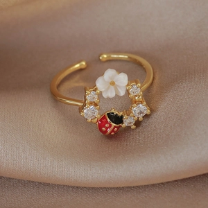 Macro detail of gold flower and ladybug ring with sparkling cubic zirconia inlay