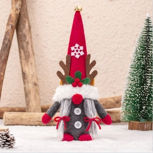 Christmas gnome ornament with reindeer antlers and red hat on a festive snowy wooden base