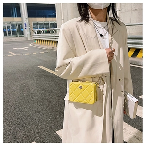 Street style shot of a yellow quilted PVC jelly bag with a metal chain strap and flap closure