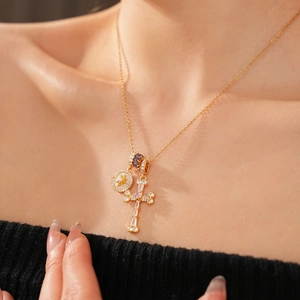 Close-up of 18k gold cross necklace with zircon and pearl pendant on model neck