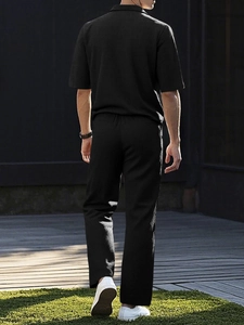 Detail of black textured short sleeve shirt and matching pants on walking male model