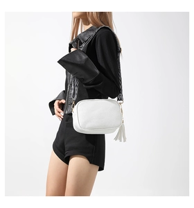 Dettaglio borsa a tracolla in pelle PU bianca con cinturino geometrico e nappa decorativa