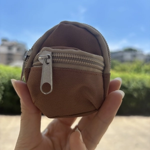 Detailed close-up of brown canvas mini backpack keychain featuring double zipper pockets