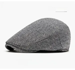 Detail of light gray newsboy cap featuring classic herringbone tweed texture and peak