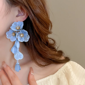 Detail of light blue floral tassel earrings with zircon studs on a female model
