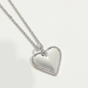 Close-up of a silver heart pendant with white mother-of-pearl and micro-set stones