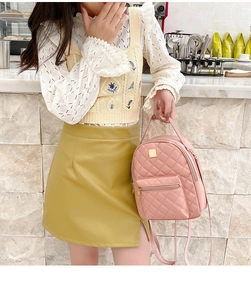 Detail of pink quilted mini backpack featuring polished metal zippers and top handle grip