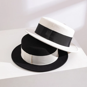 Elegant black and white wool felt boater hats with contrast ribbon on geometric stands